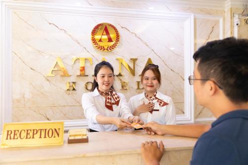 a man and a woman standing in front of a counter at Atana Airport Hotel in Ho Chi Minh City