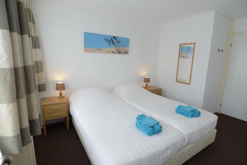 een hotelkamer met twee bedden met blauwe handdoeken erop bij Logies De Sering Texel in De Koog
