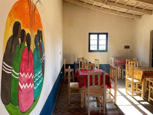 a room with tables and chairs and a large mural on the wall at Tafi del Valle Hostel in Tafí del Valle