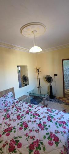 a bedroom with a bed with a floral comforter on it at DAIFLAH Guesthouse & Hostel 