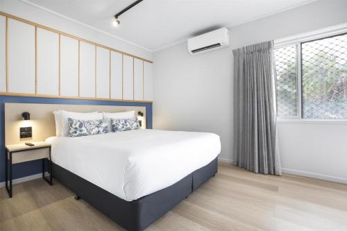 a bedroom with a large bed and a window at Nightcap at Queens Beach Hotel in Bowen