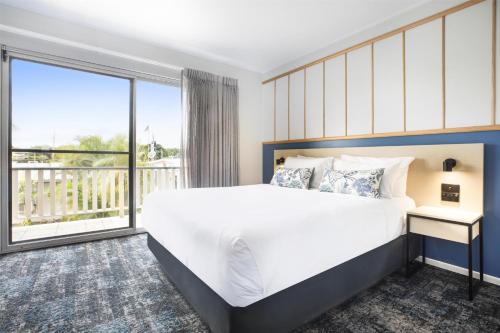 a bedroom with a large bed and a large window at Nightcap at Queens Beach Hotel in Bowen