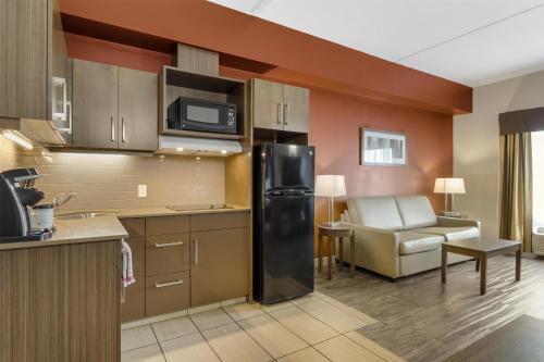 a kitchen with a black refrigerator and a living room at Best Western Plus Winnipeg West in Winnipeg
