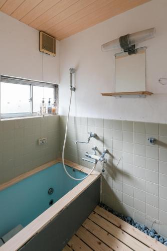 a bathroom with a bath tub with a shower at OSAKA GUEST HOUSE つながる旅の宿-en house- in Mikkaichi