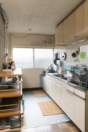 a kitchen with white cabinets and a sink at OSAKA GUEST HOUSE つながる旅の宿-en house- in Mikkaichi