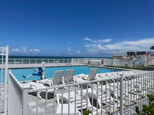 a pool with lounge chairs and the ocean in the background at Ocean Views Retreat Enjoy the Ocean View from your balcony in Daytona Beach