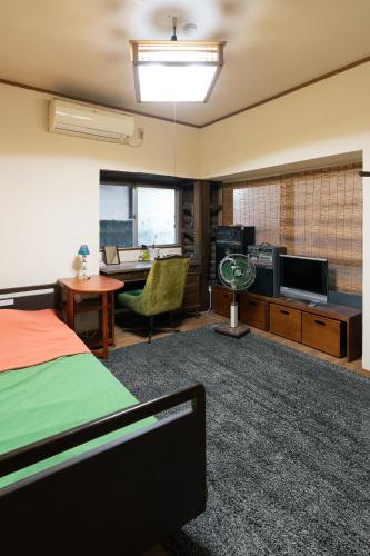 a bedroom with a bed and a desk and a tv at OSAKA GUEST HOUSE つながる旅の宿-en house- in Mikkaichi