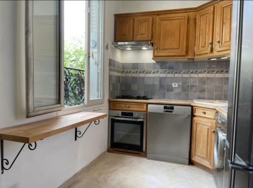 a kitchen with wooden cabinets and a stove and a window at Lovely house with garden Paris Flea Market in Saint-Ouen