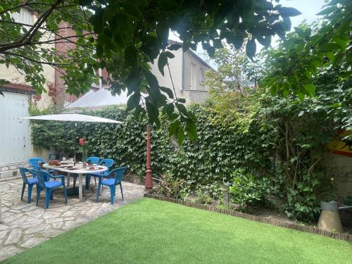 a table with chairs and an umbrella in a garden at Lovely house with garden Paris Flea Market in Saint-Ouen