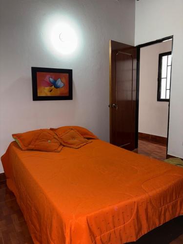 a bedroom with a bed with an orange blanket at cálido apartamento en Bello in Estación El Salto