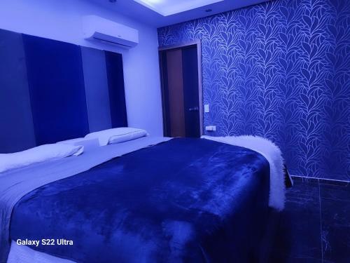 a bedroom with a bed with a blue wall at Cataleya suites blue in La Coyotera