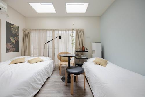 two beds in a room with a table and a chair at Lido East Shinagawa　 in Tokyo