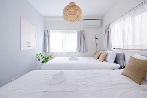 two beds in a bedroom with white walls and windows at Lido East Shinagawa　 in Tokyo