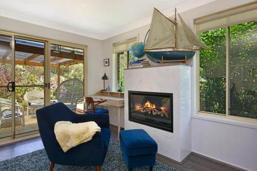 a living room with a fireplace and a blue chair at 4BR 2BA Cozy Blackheath Cottage with Firepit & Pool Table in Blackheath