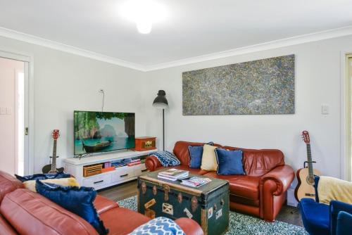 a living room with a couch and a tv at 4BR 2BA Cozy Blackheath Cottage with Firepit & Pool Table in Blackheath