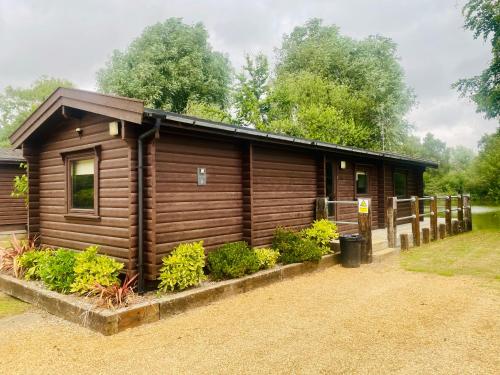 a log cabin with a fence around it at Woodlakes Park By Liv Retreats in Kings Lynn