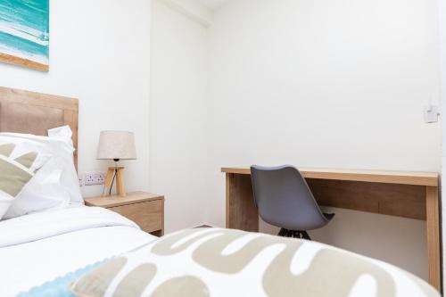 a bedroom with a desk and a chair next to a bed at CasaNova Airport Suites in Accra