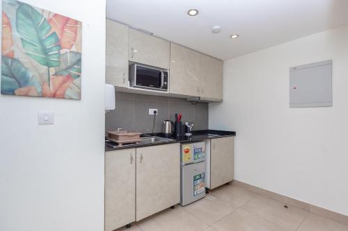 a kitchen with a sink and a microwave at CasaNova Airport Suites in Accra