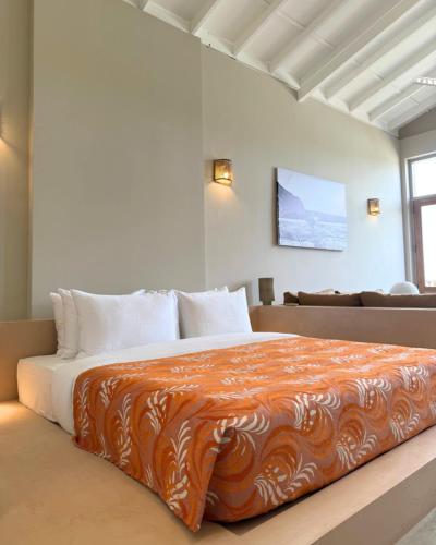 a bedroom with a large bed with an orange blanket at La Playa Studios Hiriketiya in Hiriketiya
