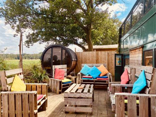 a patio with wooden benches and pillows and a tree at Woodlakes Park By Liv Retreats in Kings Lynn