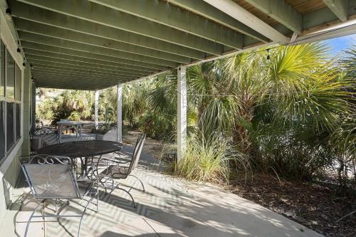 a patio with a table and chairs on a porch at Sprawling Family Home w/ Pool Table - Steps from Beach, Tennis, & Pools in Fripp Island