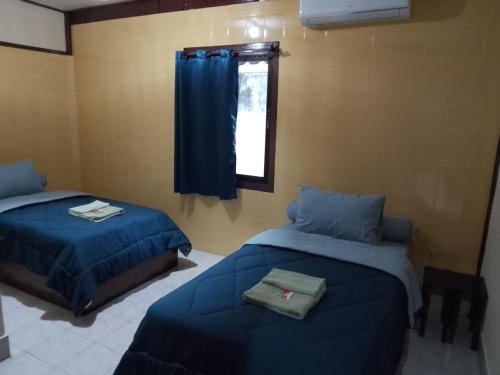 a bedroom with two beds and a window at Sabai ça Baille Guesthouse in Pakse