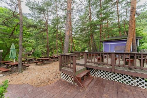 a wooden deck with benches and tables in the woods at Sangol Story Pension in Samgyo-ri