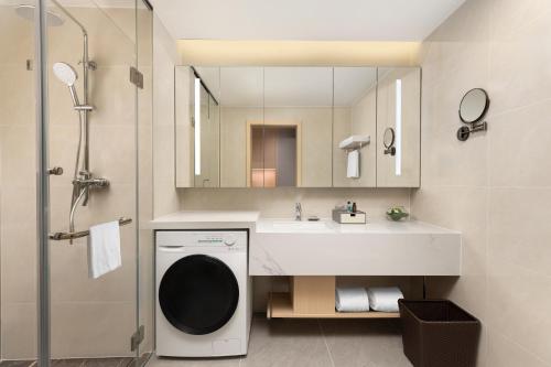 une salle de bain avec un lavabo et une machine à laver dans l'établissement Citadines Gongbei Zhuhai, à Zhuhai