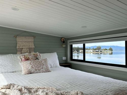 a bedroom with a large bed with a large window at Cudgeree Tiny for Two in Windang