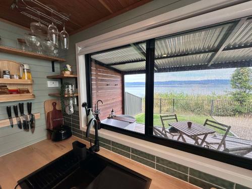 a kitchen with a large window overlooking a patio at Cudgeree Tiny for Two in Windang