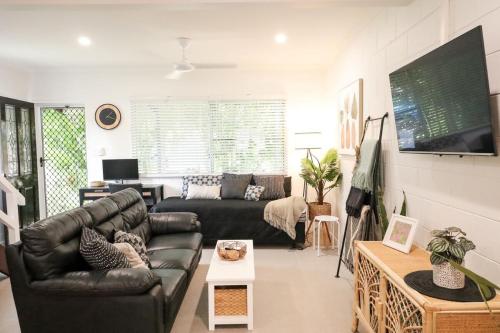 a living room with a leather couch and a tv at Whitsunday Pandanus-Stylish 2 bedroom townhouse in quiet location in Cannonvale