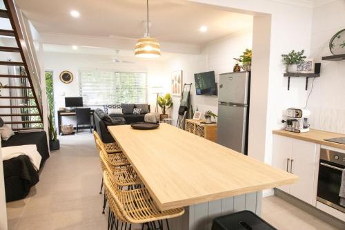 a kitchen and living room with a large wooden table at Whitsunday Pandanus-Stylish 2 bedroom townhouse in quiet location in Cannonvale