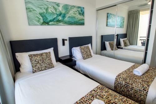 a room with two beds and a mirror at Palazzo Colonnades in Gold Coast
