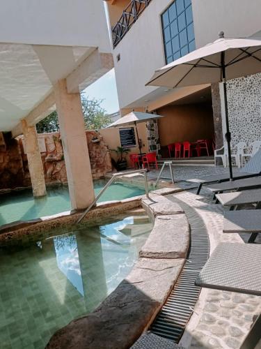 a swimming pool in a house with an umbrella at Hotel Spa el Gran Coral in San Juan Cosalá