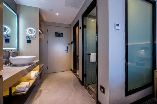 a bathroom with a sink and a glass shower at Starlit sky Hotel - Shenzhen Luohu Baoneng Center Branch in Shenzhen