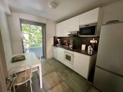 - une cuisine avec des placards blancs, une table et un réfrigérateur dans l'établissement T2 confortable à Sète avec climatisation et WIFI - FR-1-338-598, à Sète