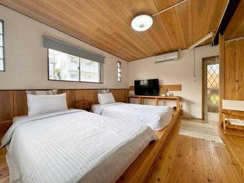a bedroom with two beds and a tv in it at 宿屋lotus in Ishigaki Island