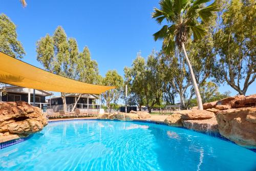 a swimming pool in a resort with a palm tree at RAC Exmouth Cape Holiday Park in Exmouth