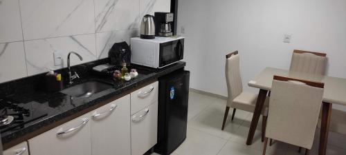 a kitchen with a sink and a microwave at Apartamento Central in Ametista do Sul