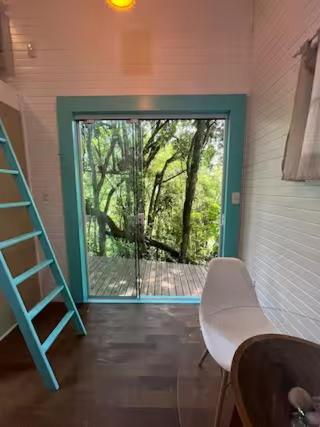 a room with a ladder and a door with a window at Tiny House Garopaba in Garopaba