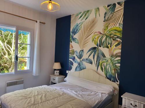 - une chambre avec un lit orné d'une fresque murale tropicale dans l'établissement Maison avec piscine privée, près de la plage, à Longeville-sur-Mer - FR-1-336-157, à Longeville-sur-Mer