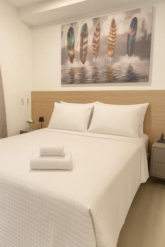 a bedroom with a large white bed with a painting on the wall at Confortável Apartamento próximo ao metrô Tucuruvi in Sao Paulo