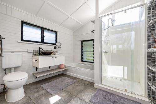 a white bathroom with a toilet and a shower at Charming Queenslander Retreat in Mundingburra in Rosslea