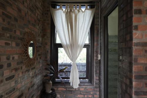 a window with a white curtain in a brick wall at mehome in Cư Chinh