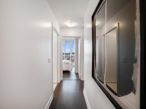 un pasillo con paredes blancas y un espejo grande en Nobu Suites - Toronto's Entertainment District, en Toronto