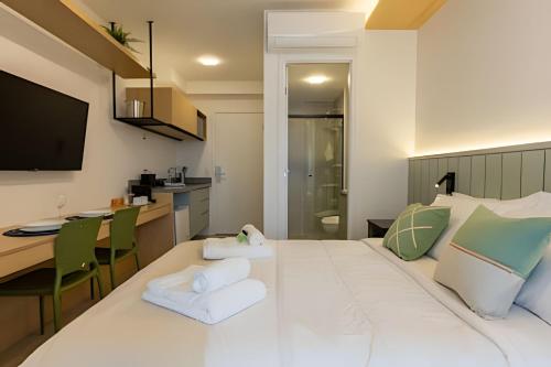 a large white bed in a room with a kitchen at Nik Perdizes in Sao Paulo