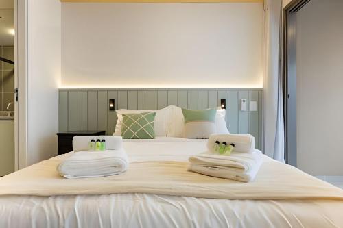 a large white bed with two towels on it at Nik Perdizes in Sao Paulo
