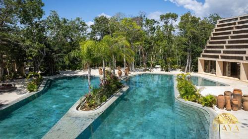 a swimming pool with blue water and palm trees at Peregrina Tulum 317 1-Bedroom Condo in Tulum
