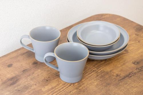 three cups and plates on a wooden table at JR Kamata Station is a 3-minute walk, Shinagawa is 7 minutes by train, and Keikyu Kamata Station has direct access to Haneda Airport, Tokyo, Shinagawa, Yokohama, and Ueno in Tokyo