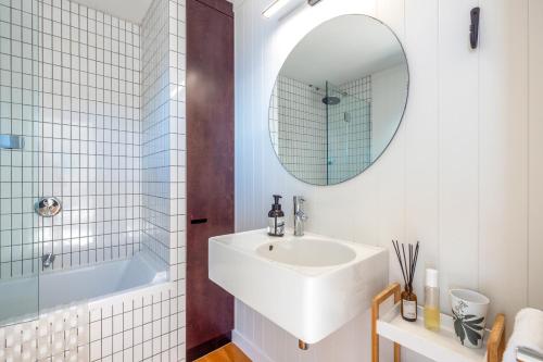 Un baño con un lavabo blanco y un espejo. en Clifftop Sanctuary - Stay Waiheke, en Oneroa